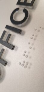 Raised black letters and Braille on metal